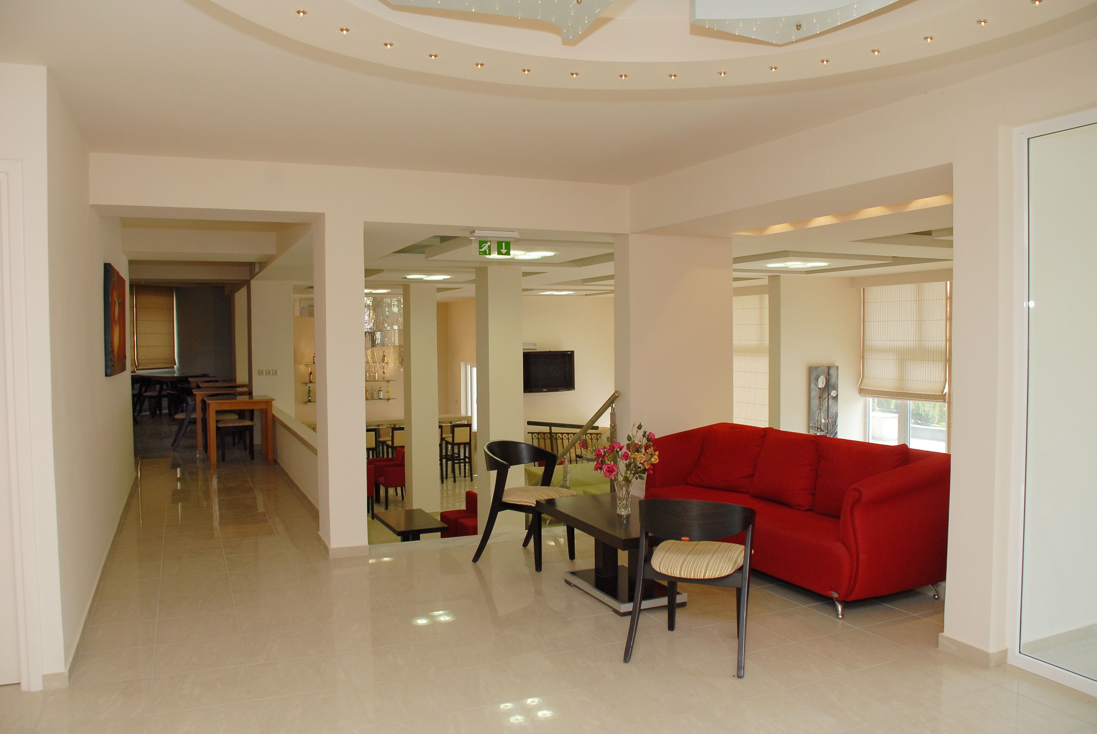 Un hall d’entrée spacieux avec un canapé rouge, un coin repas et un design moderne au niveau du plafond.