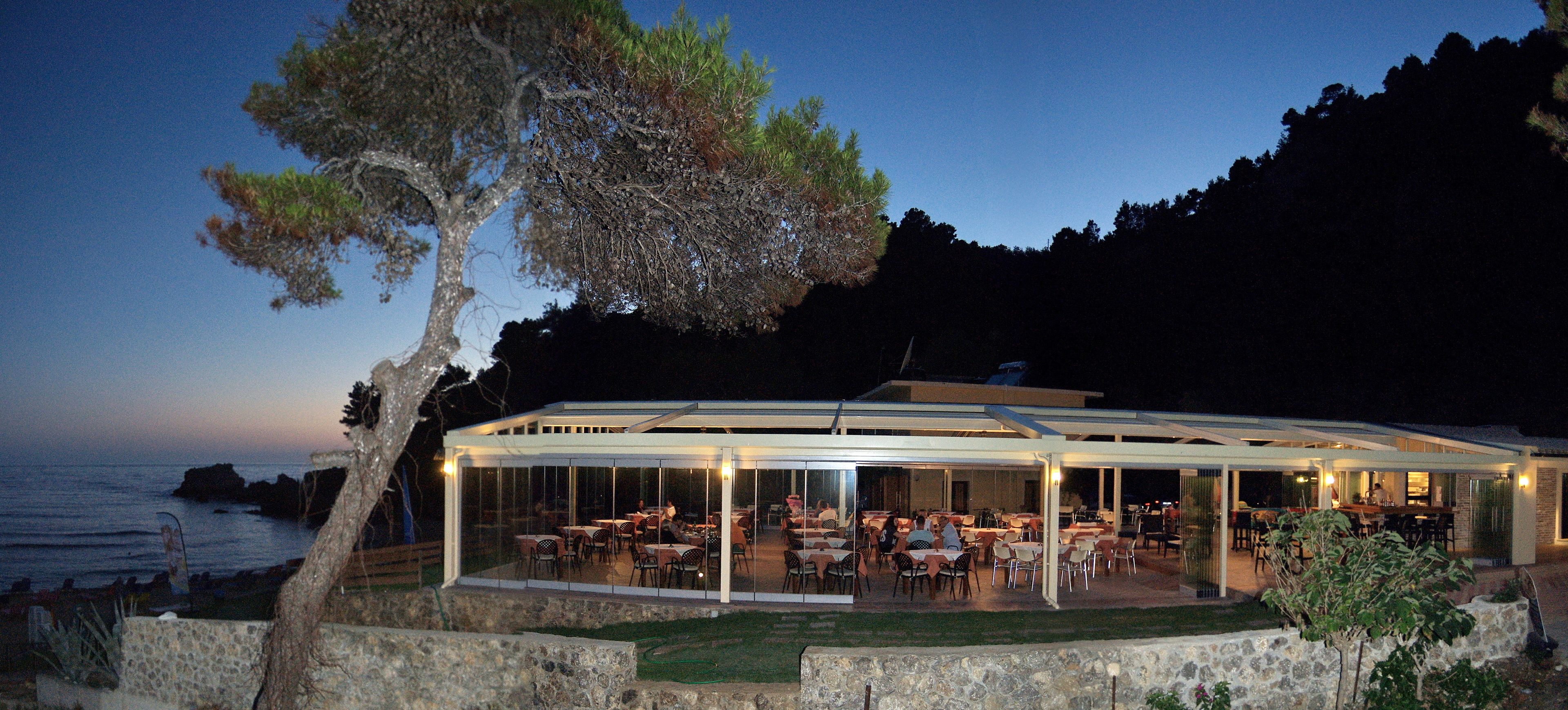 An outdoor restaurant with tables and chairs, overlooking the ocean.