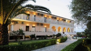 A multi-story hotel with a central courtyard, balconies, and a stone pathway. - Primavera Hotel (Corfu)