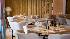 A restaurant with multiple tables set with plates, glasses, and a vase with dried plants. - Primavera Hotel (Corfu)