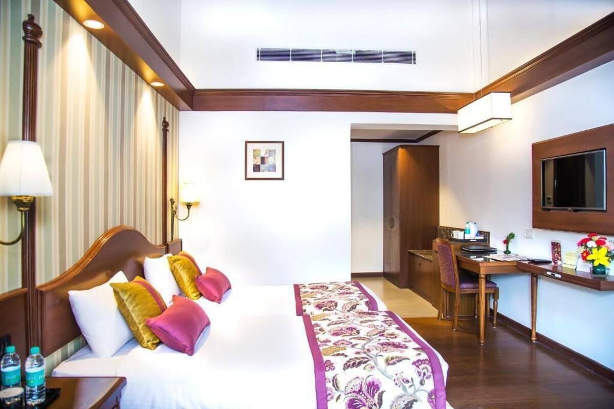 A hotel room with a bed, desk, and television.