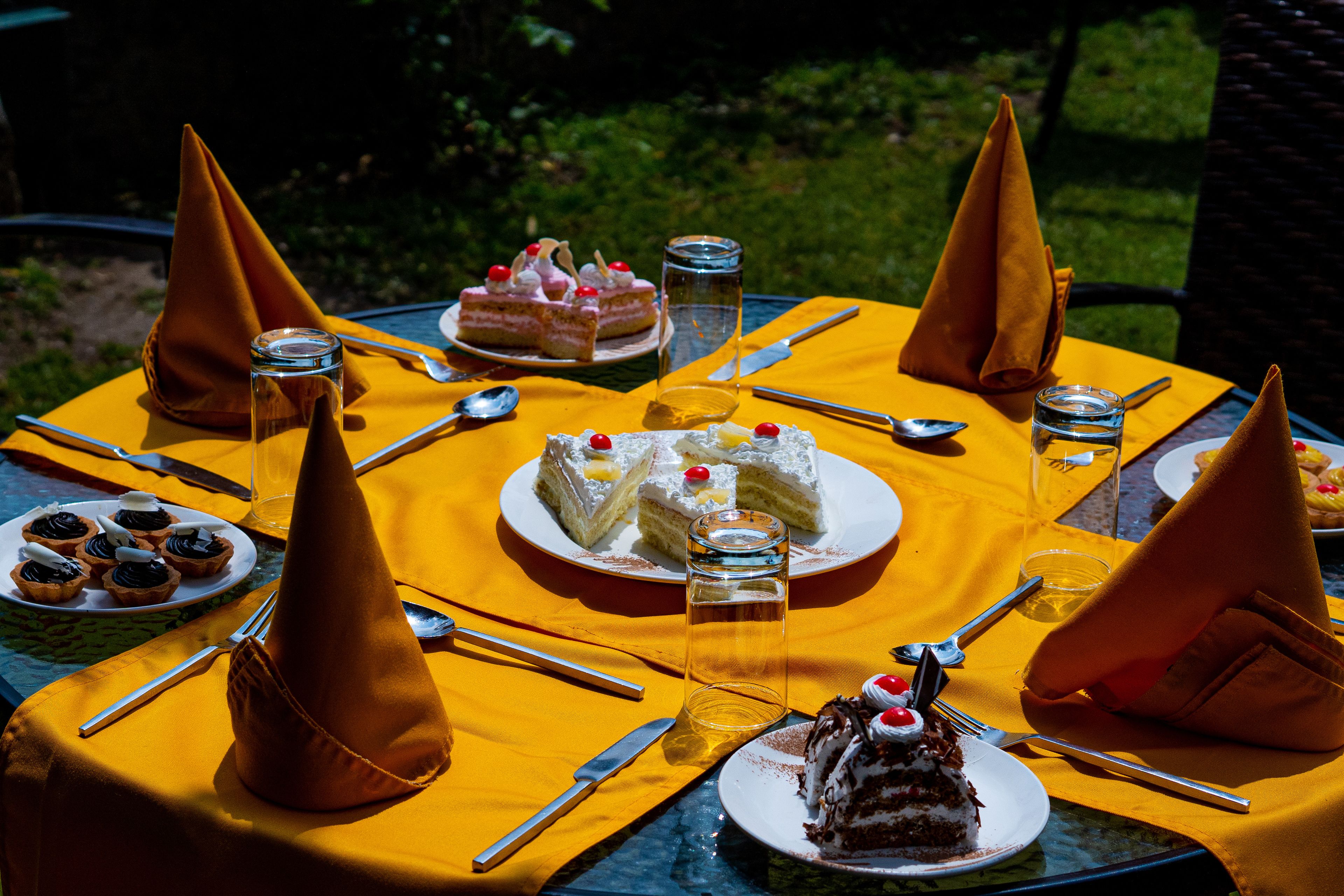 Una mesa redonda preparada para una comida, con diversos postres y utensilios.