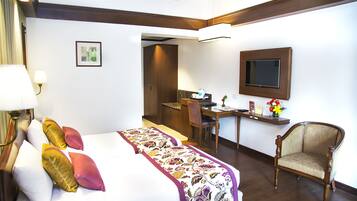 A hotel room with a bed, a desk, a chair, and a television.