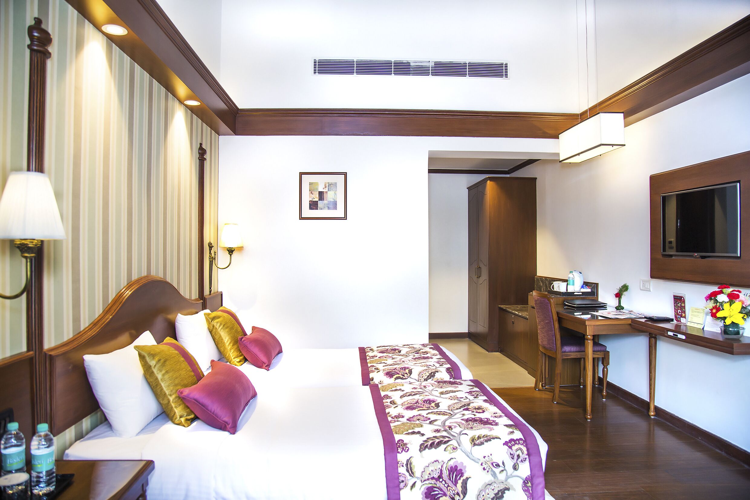 A hotel room with a bed, desk, chair, and a television.
