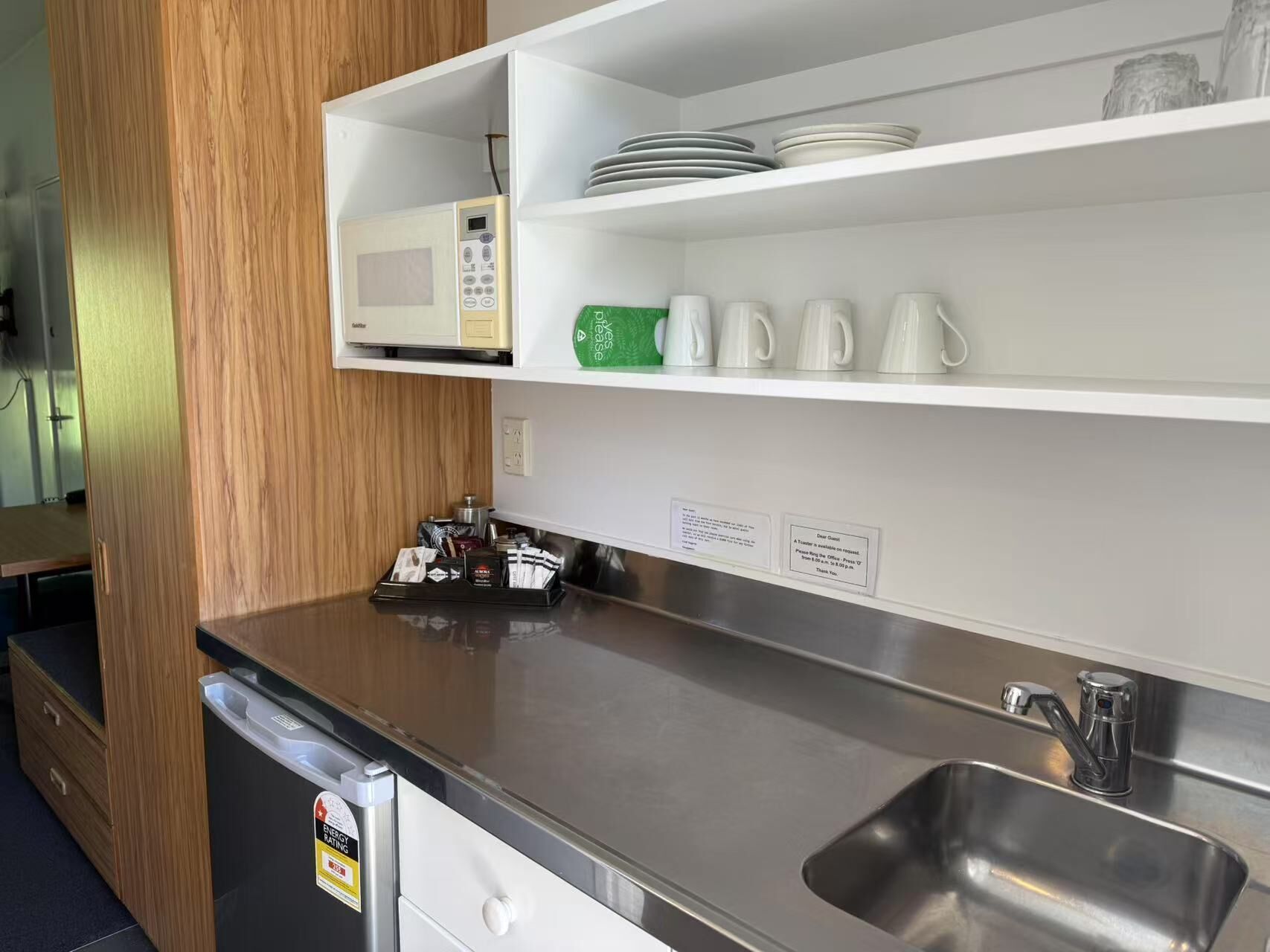 Een moderne keuken met een magnetron, koffiezetapparaat en een spoelbak.