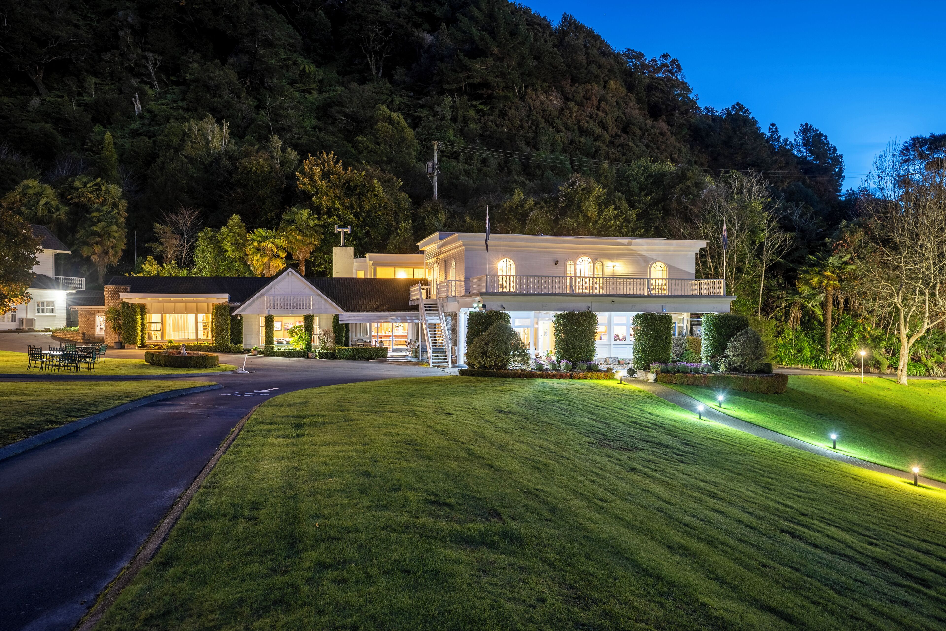 A large, two-story house with a well-maintained lawn and a driveway leading to the entrance.