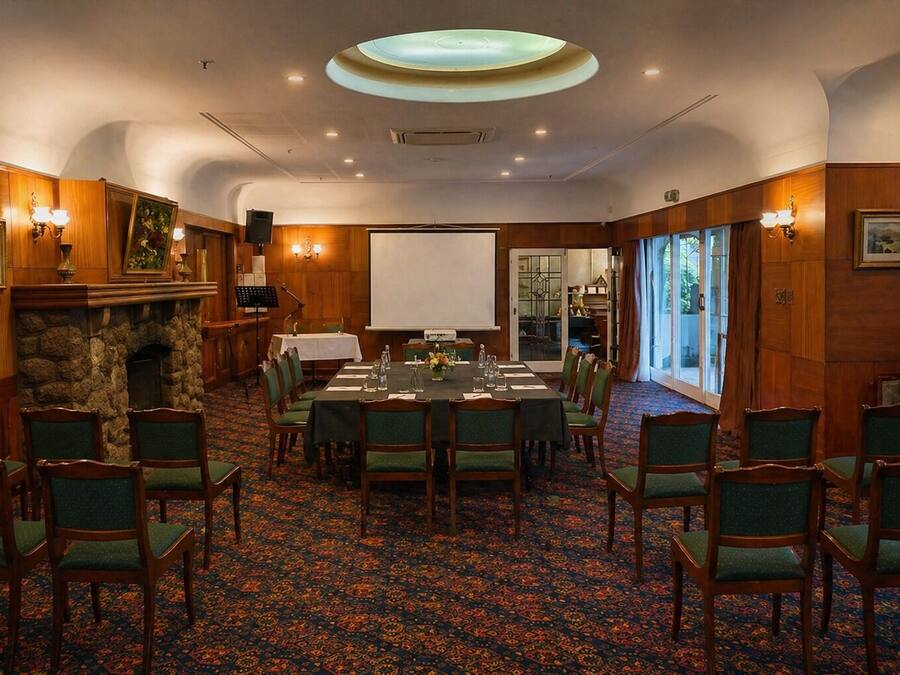 A conference room with a long table, chairs, a fireplace, and a large window.