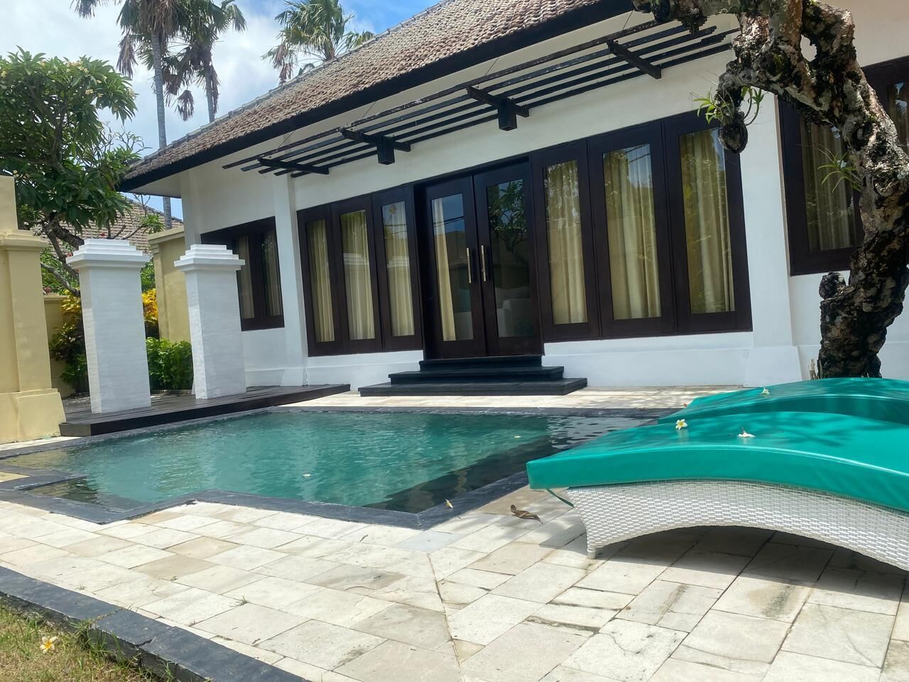 Et hus med swimmingpool, overdækket terrasse og have.