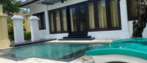 Et hus med swimmingpool, overdækket terrasse og have.