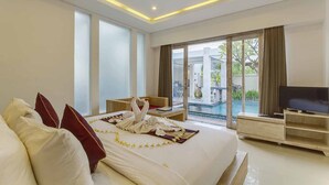A modern hotel room with a large bed, a TV, and a view of a swimming pool. - The Tukad Villa (Seminyak)