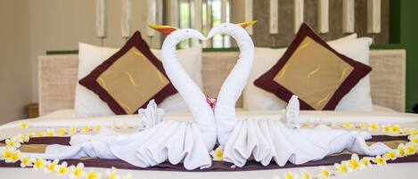 A hotel room with a bed adorned with towels shaped like swans and yellow flowers.