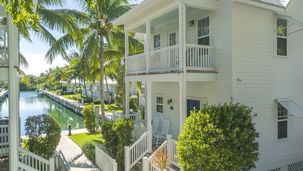 A white two-story building with a balcony, a dock, and a canal. - Coral Lagoon Resort Villas & Marina by KeysCaribbean (Marathon)
