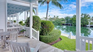 A covered outdoor area with wooden furniture and a view of a lake. - Coral Lagoon Resort Villas & Marina by KeysCaribbean (Marathon)
