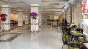 A spacious lobby with marble floors, a reception desk, and a seating area with tables and chairs. - Dong Kinh Hotel (Ho Chi Minh City)