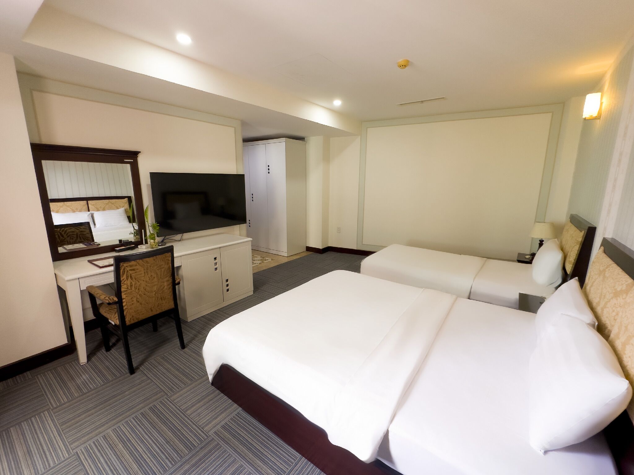 Ein Hotelzimmer mit Bett, Schreibtisch, Fernseher und Kleiderschrank.