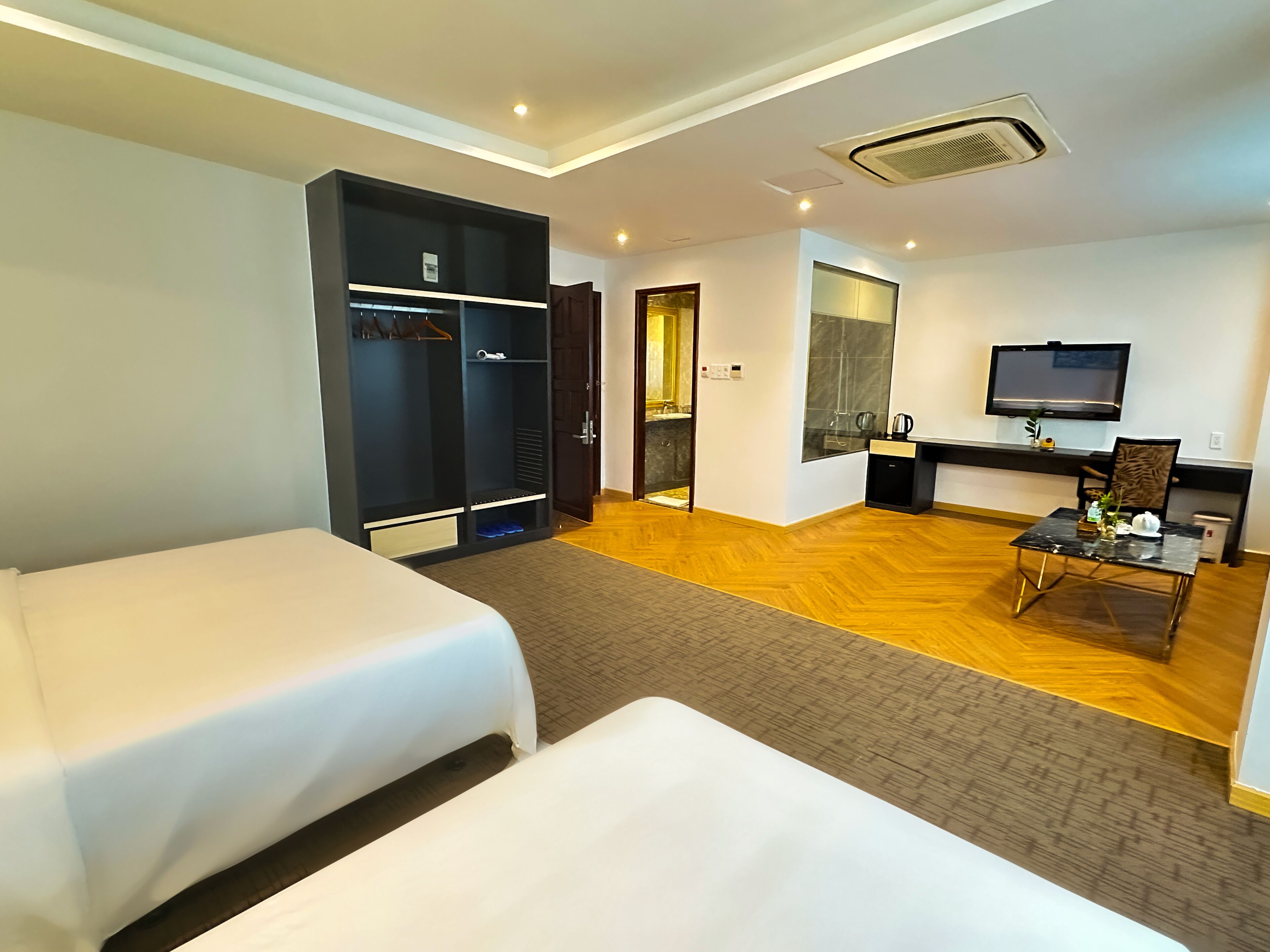 Una habitación de hotel con dos camas, un escritorio con una silla, un televisor y un armario.
