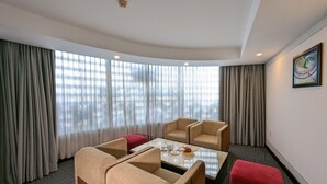 A hotel room with a seating area featuring two beige armchairs and a small table with a red ottoman. - Dong Kinh Hotel (Ho Chi Minh City)