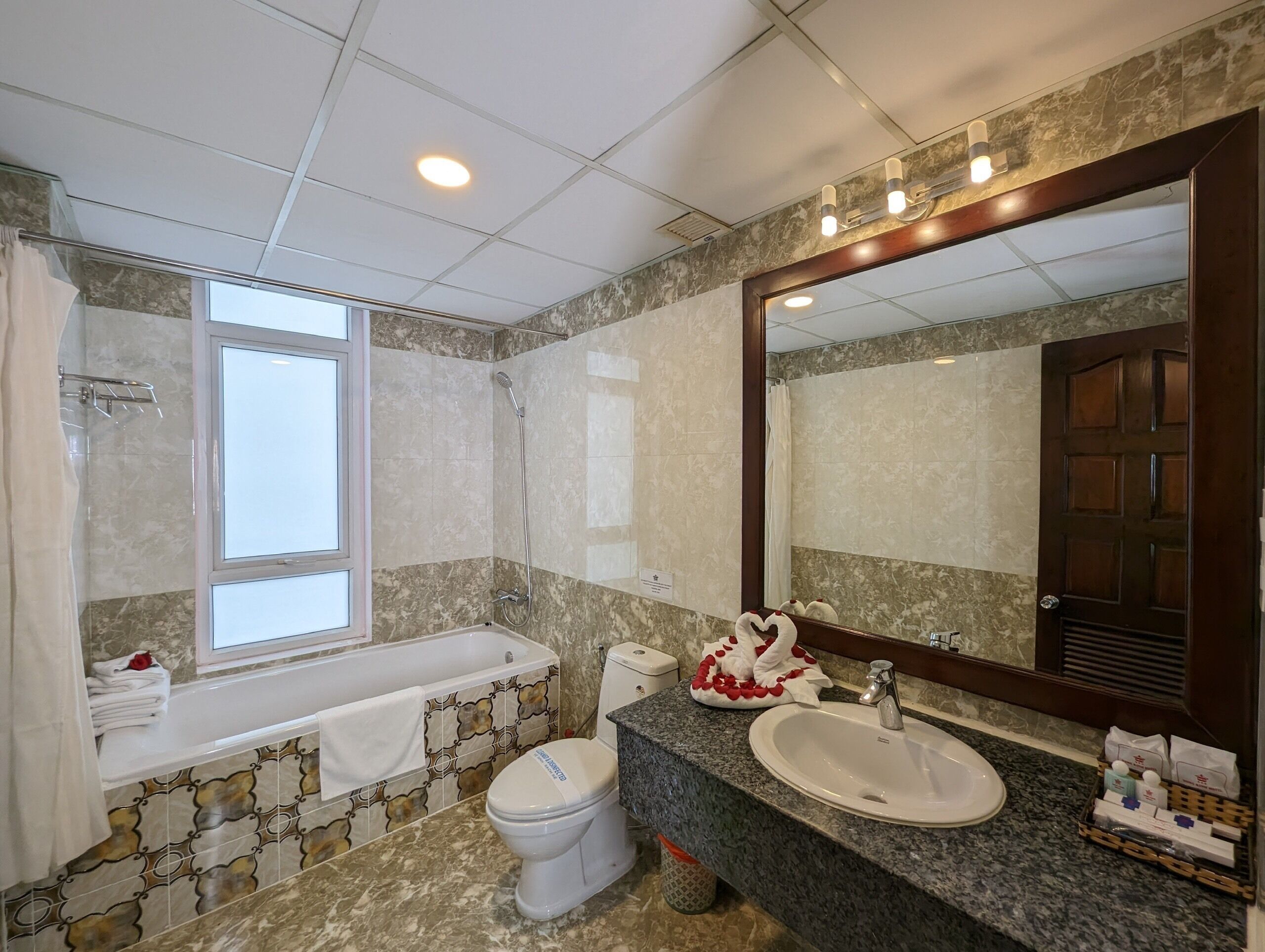 A bathroom with a bathtub, toilet, sink, and a large mirror.