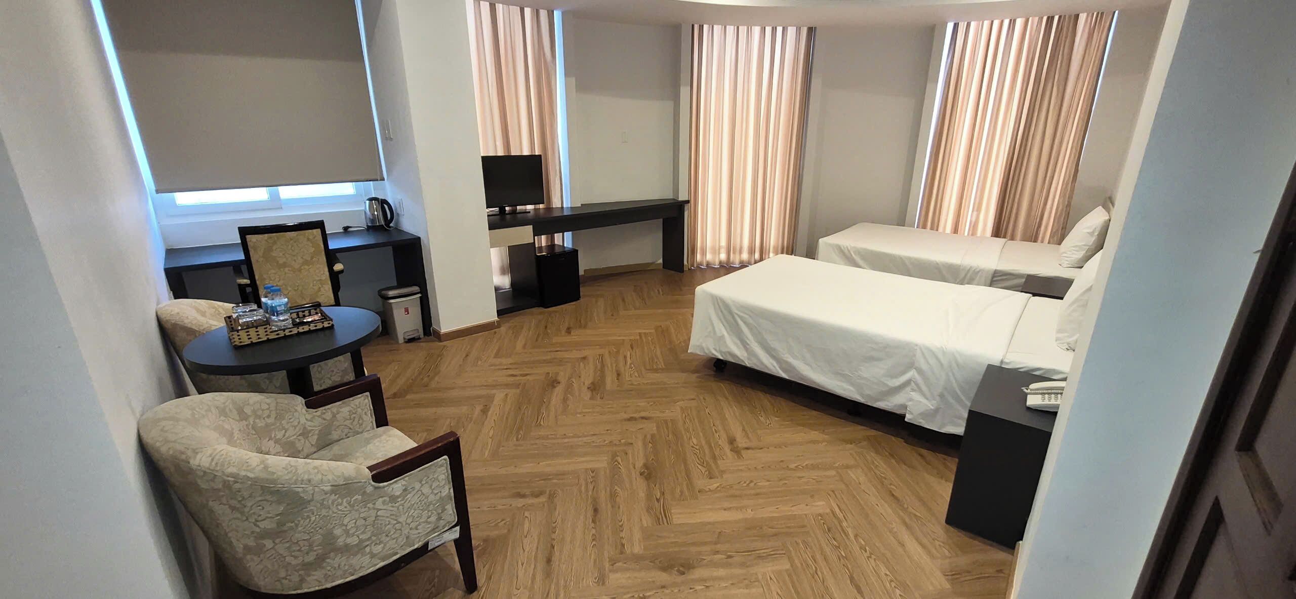 Una habitación de hotel con escritorio, silla, dos camas y televisión.