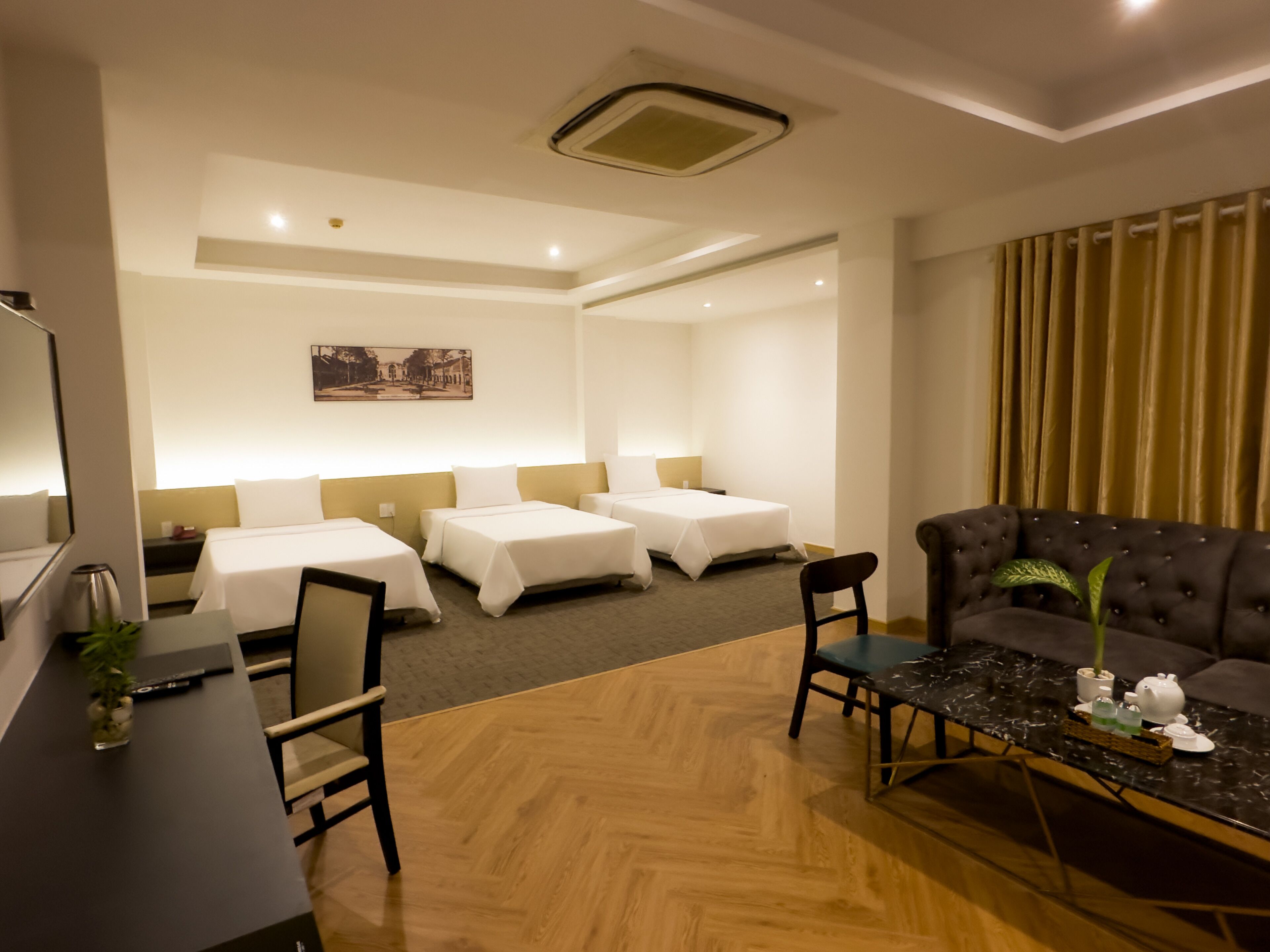 Una habitación de hotel con dos camas individuales, un sofá, una mesa de comedor y un televisor.