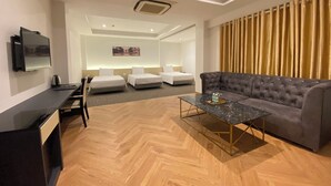 A modern hotel room with a sofa, a coffee table, a TV, and a bed. - Dong Kinh Hotel (Ho Chi Minh City)