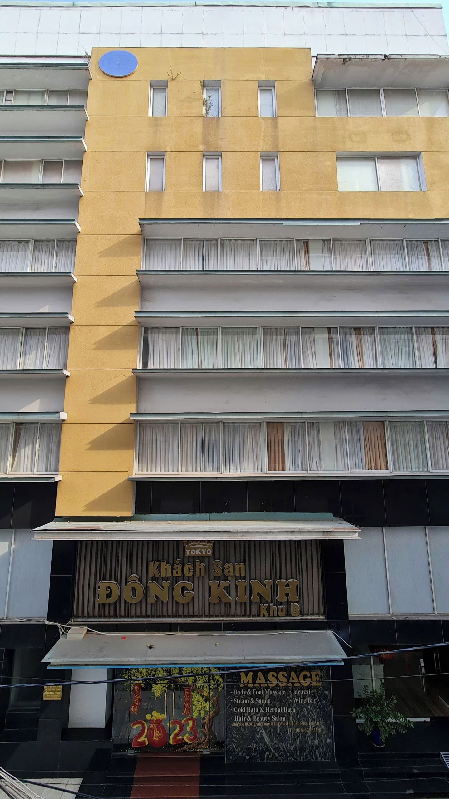 Un edificio con un cartel que dice 'Tokyo Khang San Dong Kinh Khu B' y un anuncio de servicios de masaje.