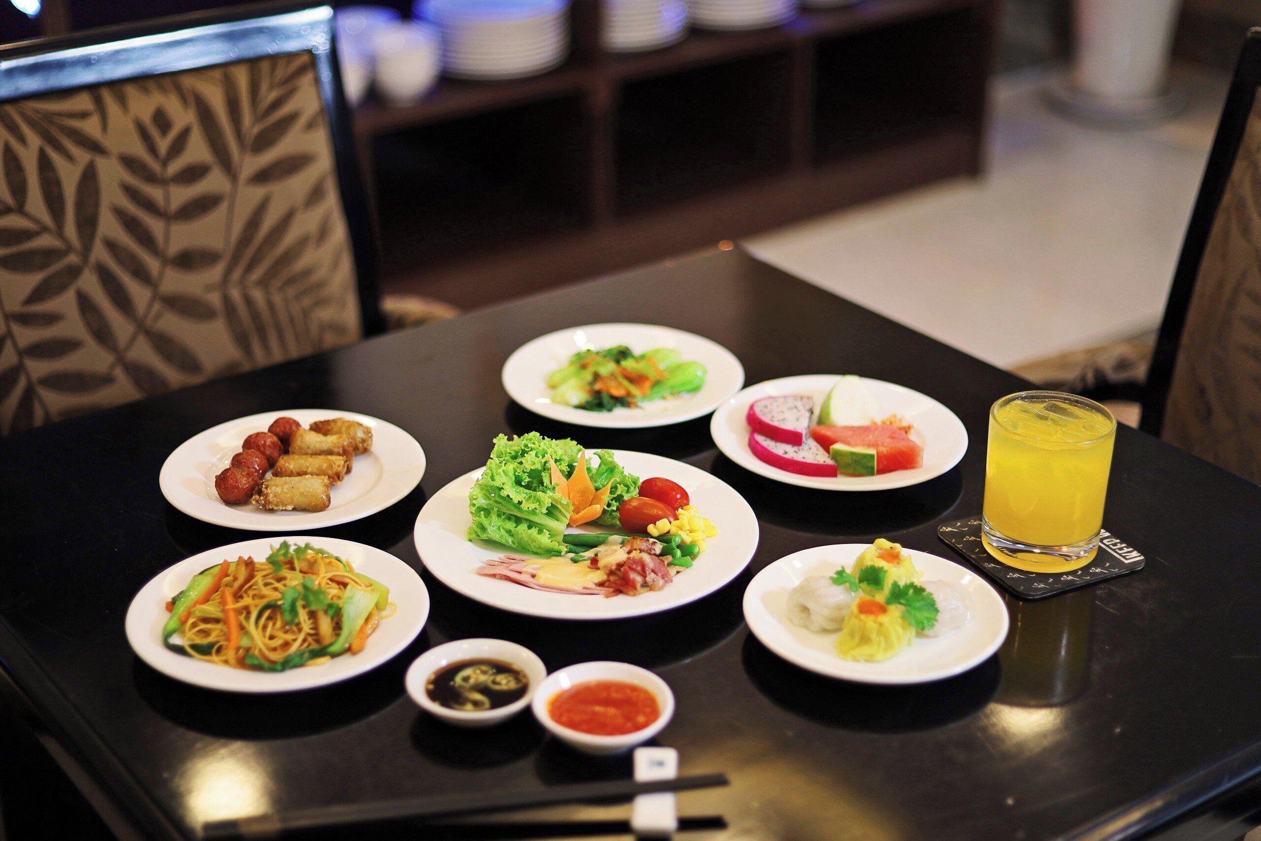A table with various dishes and a glass of orange juice.