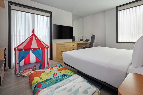 A hotel room with a bed, a desk, a chair, a TV, and a children's play tent. - Aloft by Marriott Bangkok Sukhumvit 11 (Bangkok)