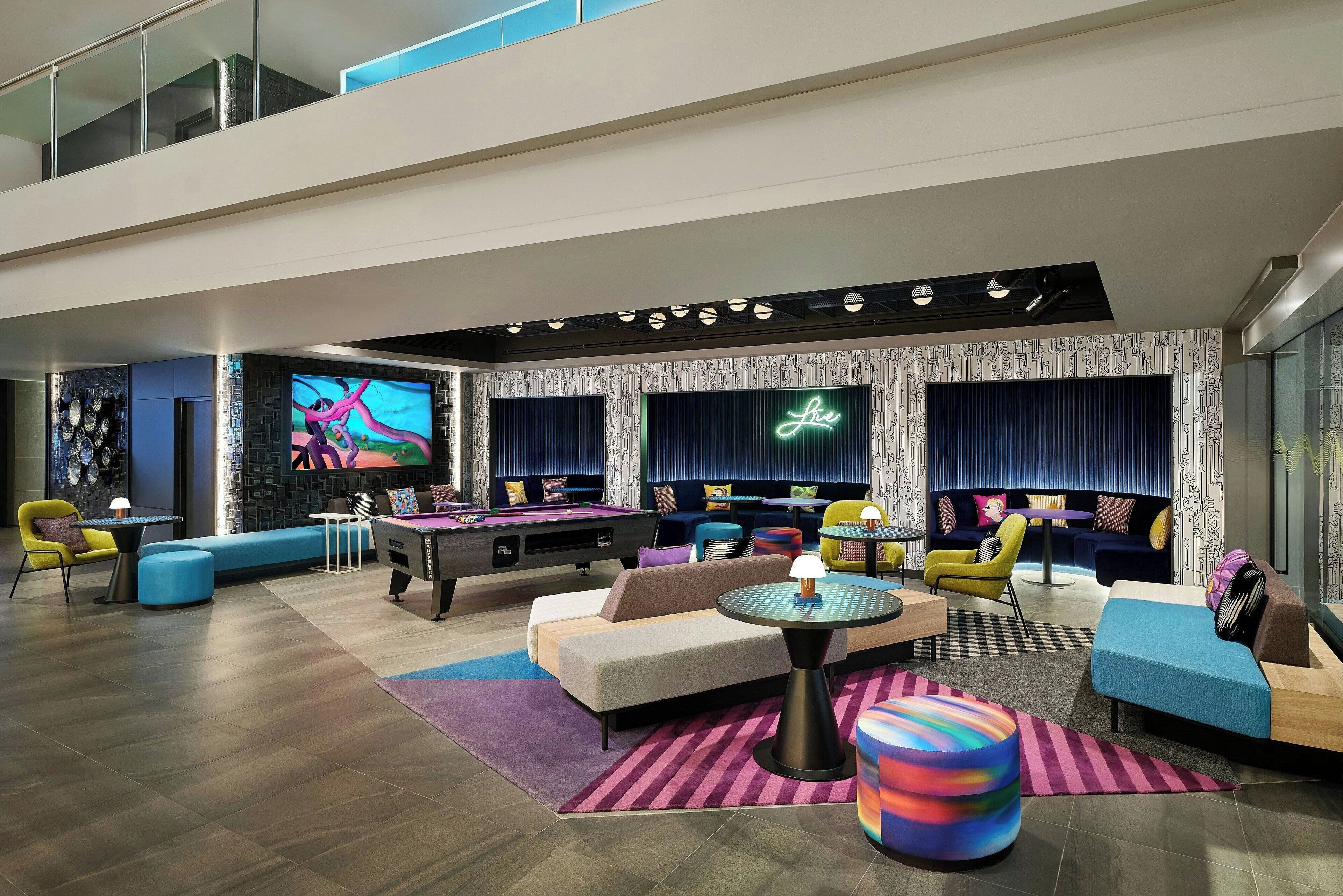 A modern indoor space with a pool table, sofas, and a neon sign.
