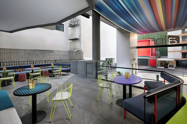 A modern indoor space with seating areas, tables, and a staircase.