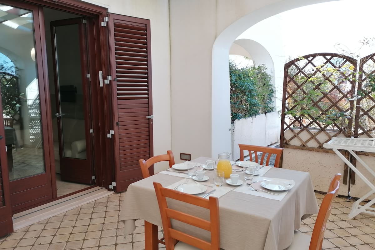 A dining area with a table set for four, a glass of orange juice, and a wooden chair.