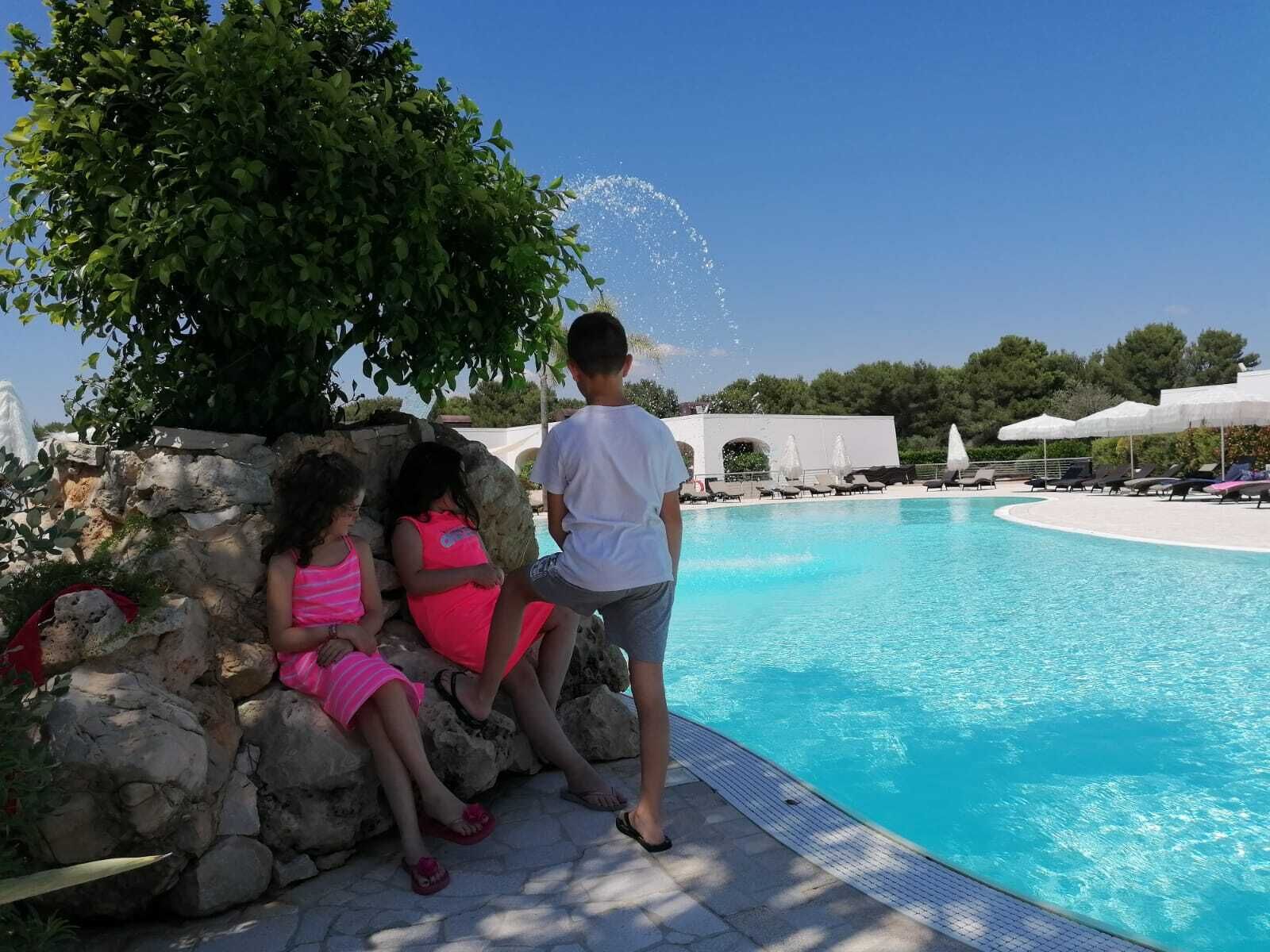 Un espace piscine doté d’une piscine à l’eau cristalline, de sièges en pierre et de parasols.