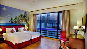 Habitación de hotel con una cama grande, una silla, un escritorio y vistas al océano.