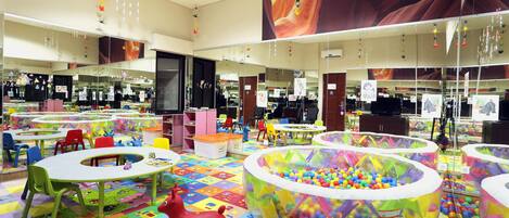 A children's play area with colorful play mats, tables, chairs, and a ball pit.