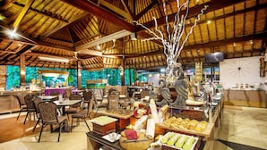 Zona de bufé con diferentes opciones de comida, mesas y una escultura decorativa de árbol.