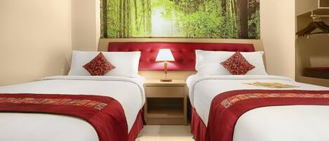 Habitación de hotel con dos camas, cabecero rojo, mesita de noche con lámpara y vistas a un bosque.