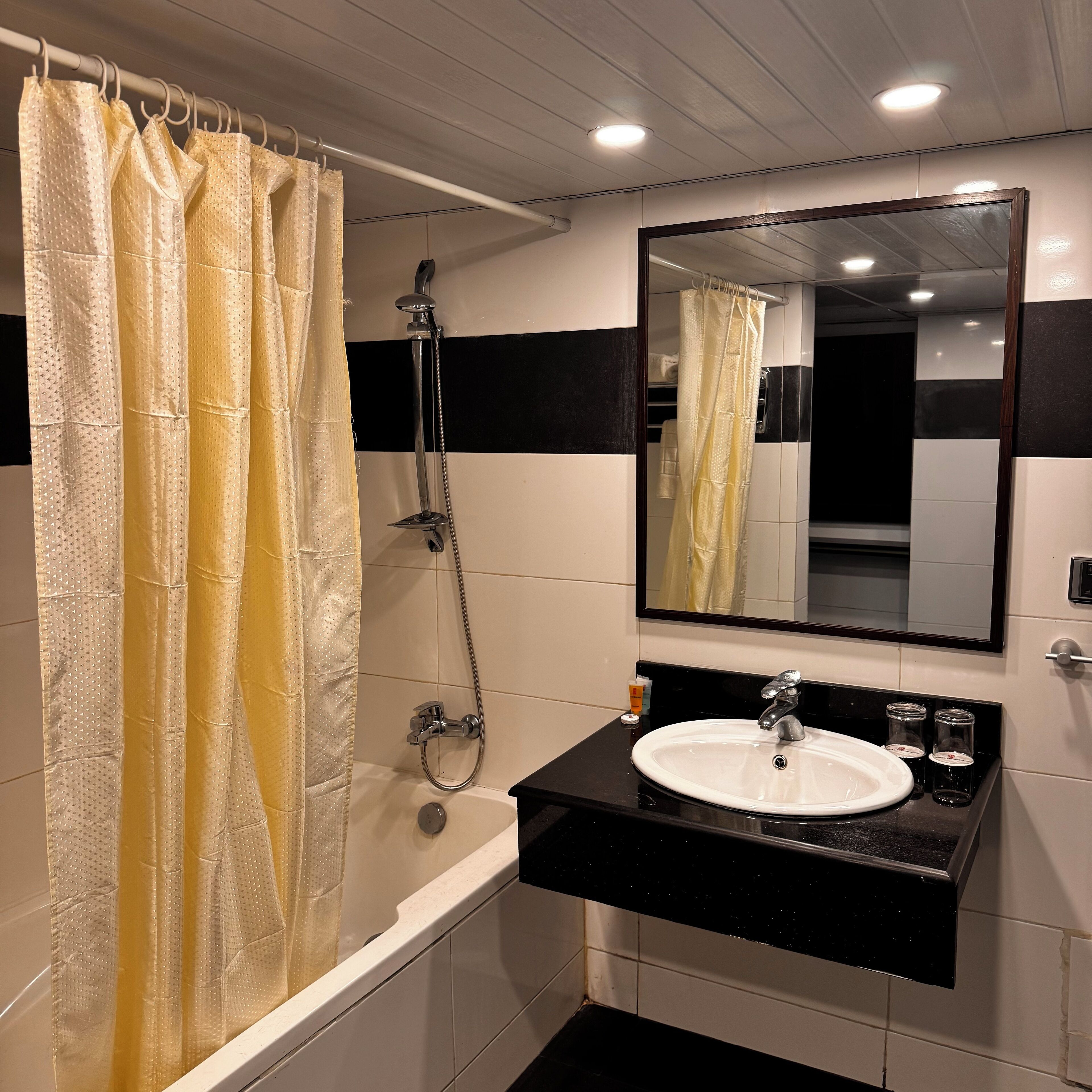 A bathroom with a bathtub, a shower, a sink, and a mirror.