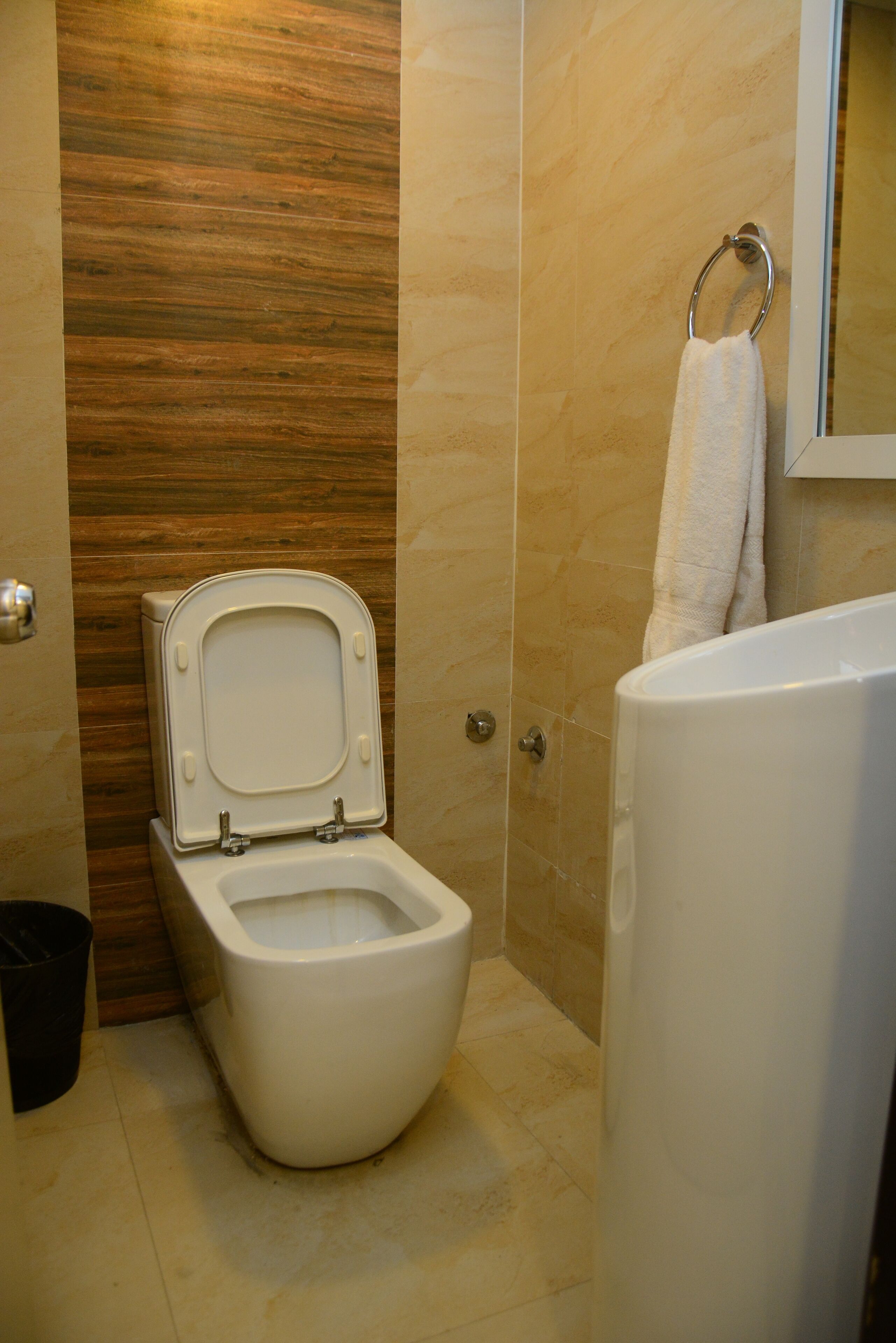 A modern bathroom with a toilet, a bathtub, and a towel hanging on a ring.