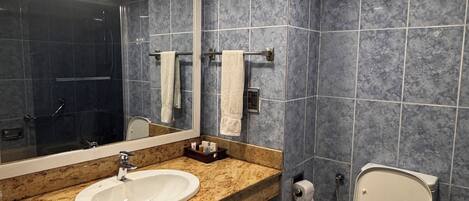 Un baño moderno con encimera de granito, dos lavamanos, un inodoro y un espejo grande.