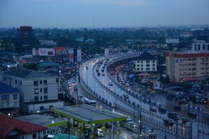 A busy urban highway with multiple lanes of traffic, a gas station, and surrounding buildings. - Presidential Hotel (Port Harcourt)