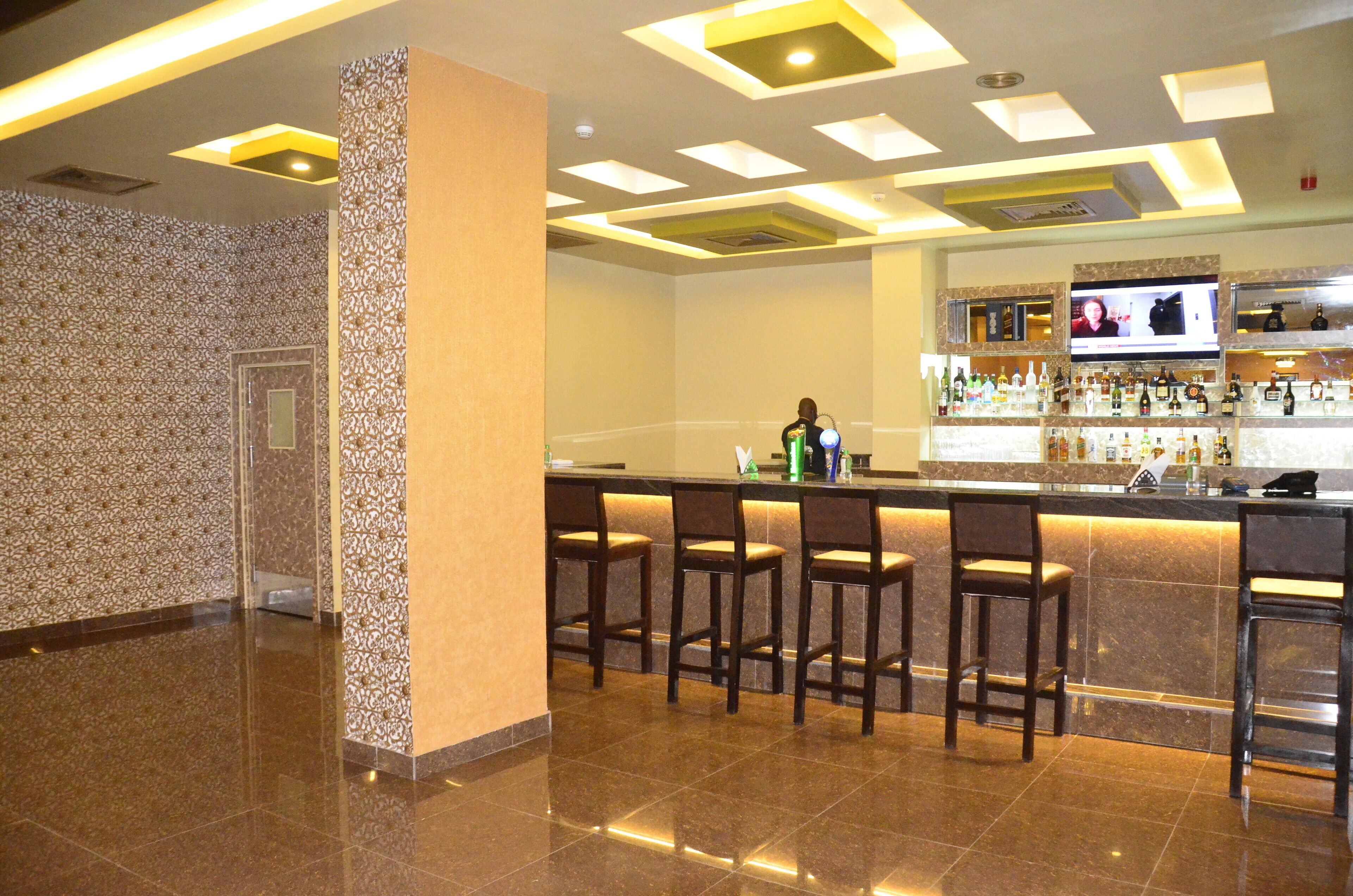 A bar area with a counter, multiple stools, and a television screen.