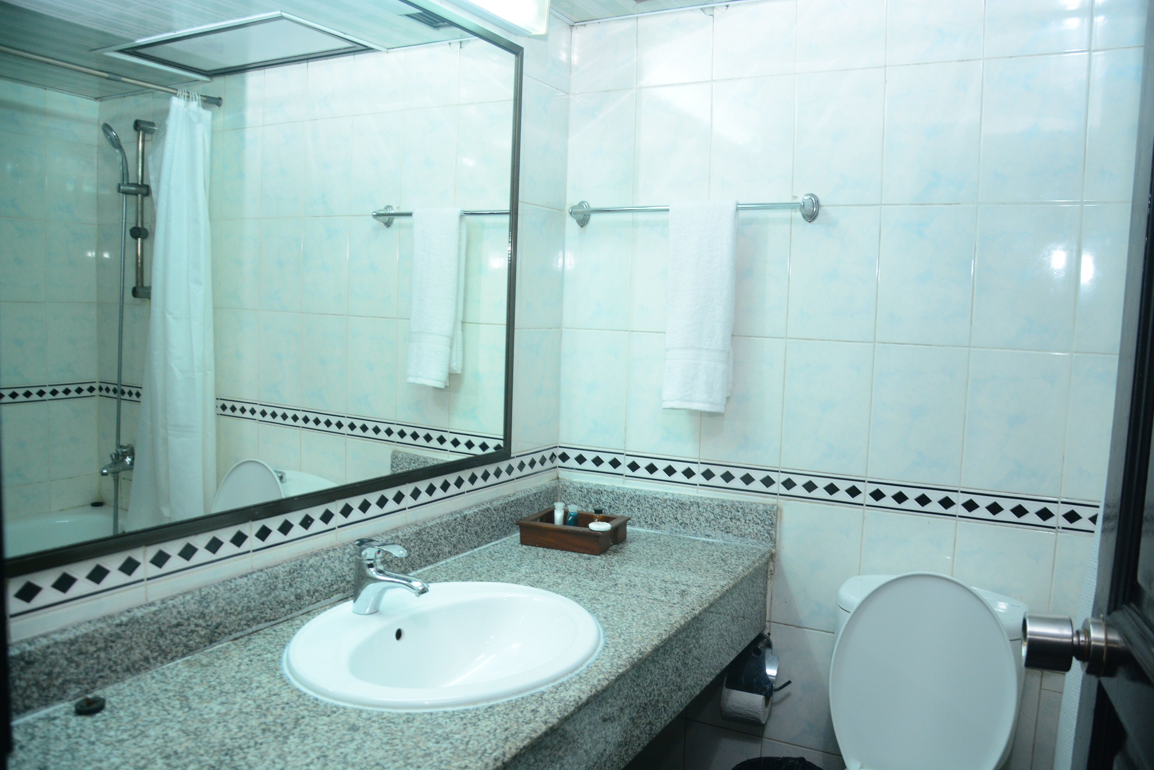 A bathroom with a sink, mirror, shower, and toilet.