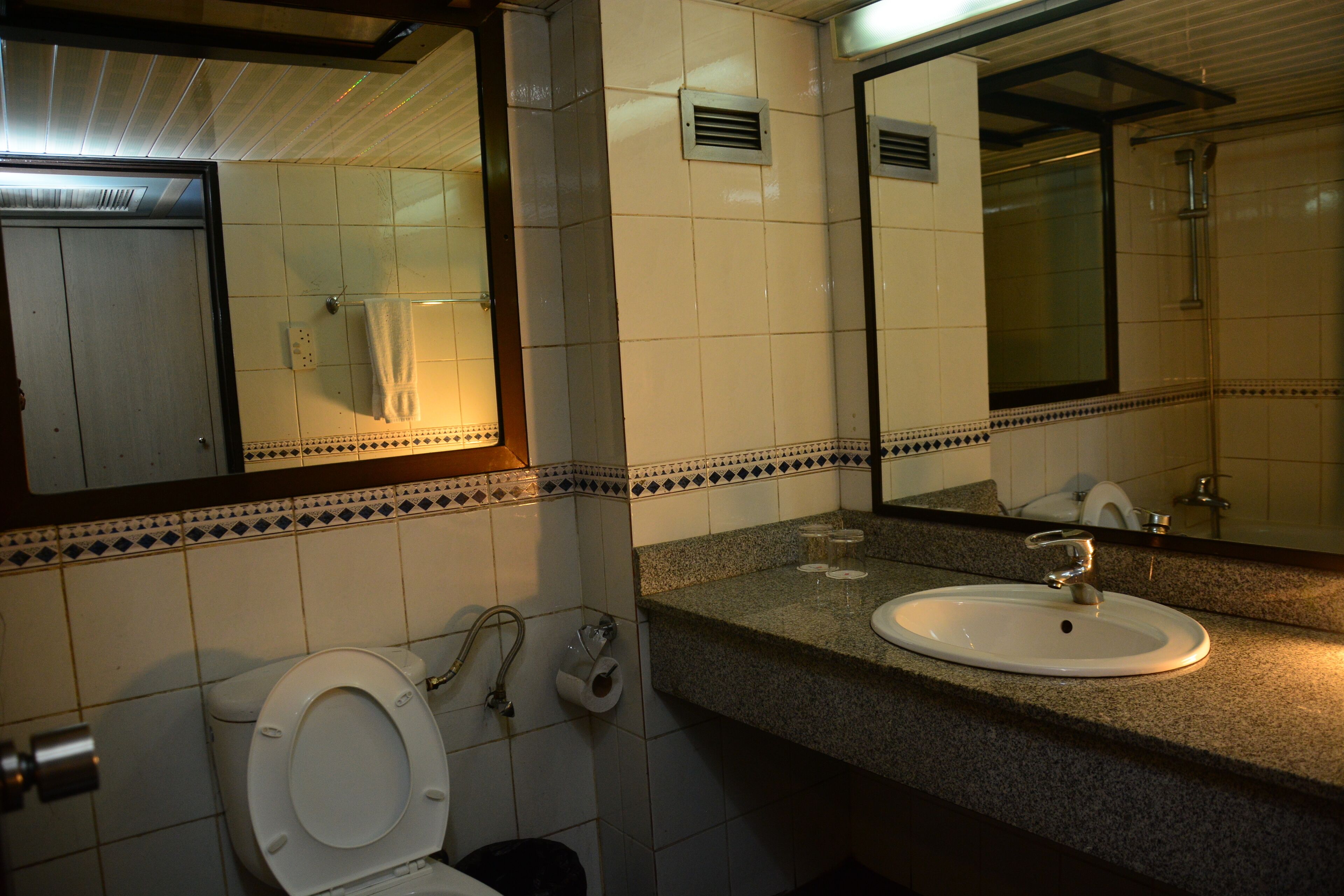 A bathroom with a toilet, sink, mirror, and tiled walls.