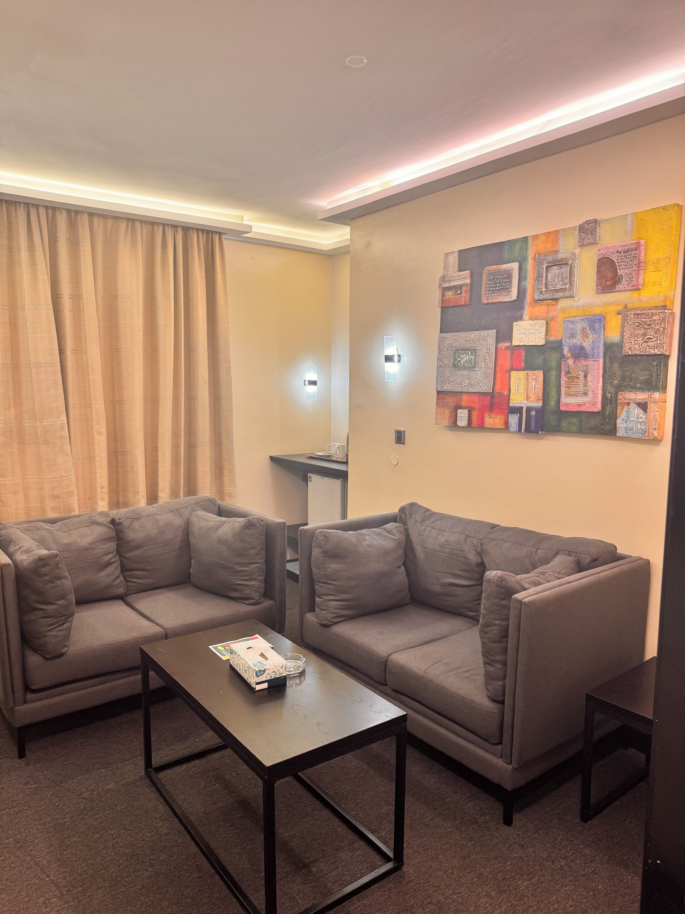Ein modernes Wohnzimmer mit einer Eckcouch, einem Couchtisch und einer Wand mit dekorativer Kunst.