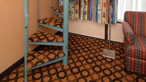 Une pièce avec un escalier en colimaçon, une moquette à motifs, une lampe et un canapé.