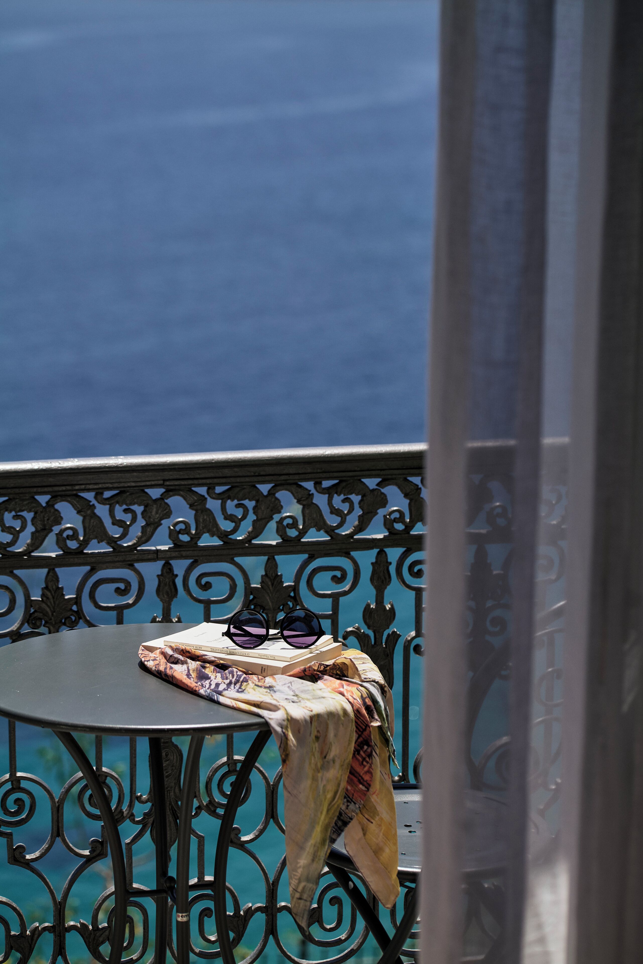 A balcony with a table, a patterned cloth, and sunglasses.