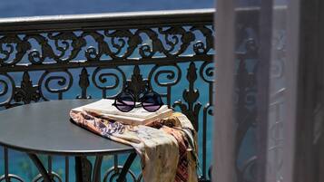 A balcony with a table, a patterned cloth, and sunglasses.