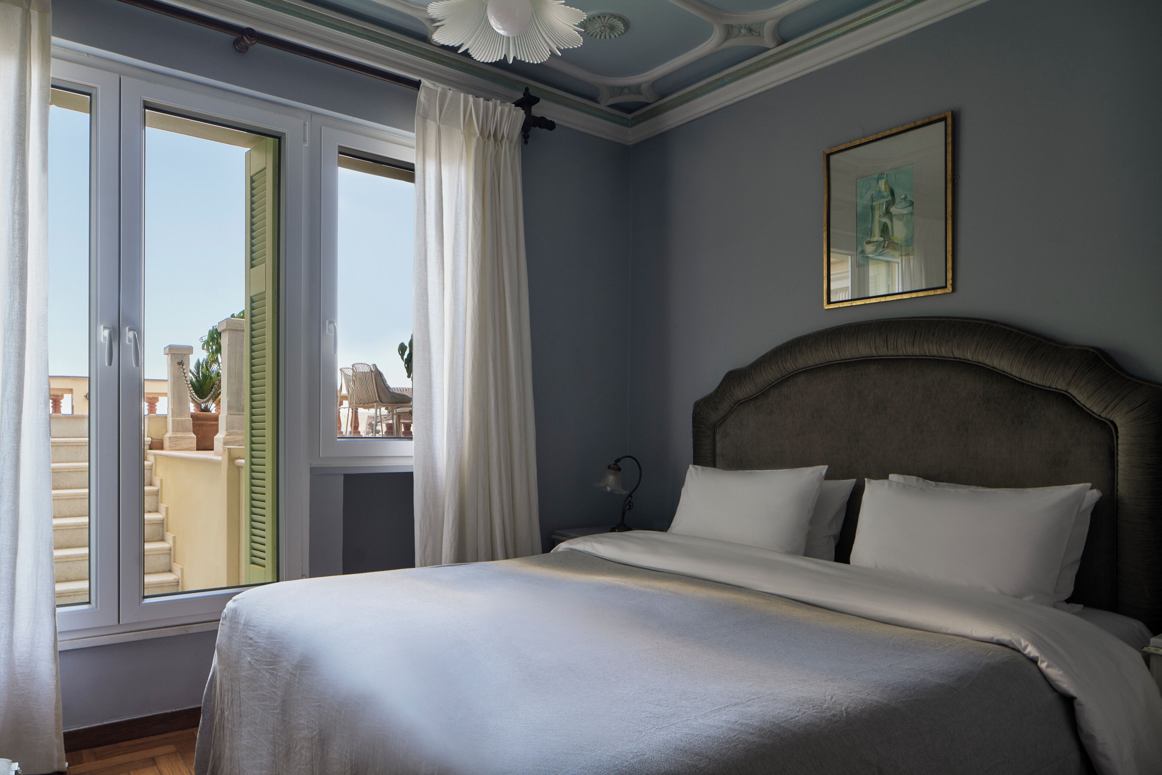 Un dormitorio con una cama grande, una ventana con cortinas y un cuadro en la pared.