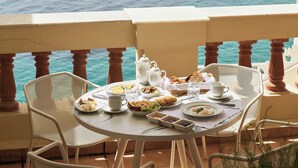 A table set for breakfast with a view of the sea and hills.