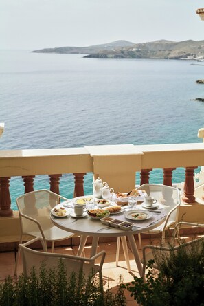 A table set for breakfast with a view of the sea and hills.